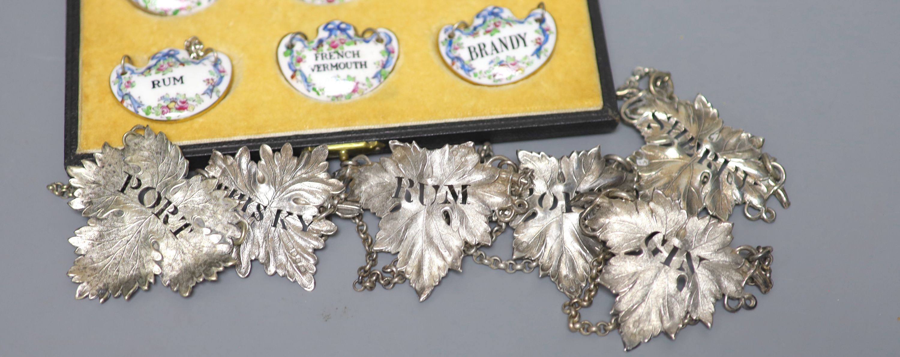 A set of four Victorian silver leaf shaped wine labels, London, 1874, 64mm, one other Victorian silver wine lable, a plated wine label and a set of six ceramic wine labels by Goode & Co.